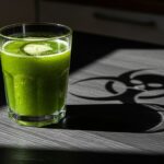 A glass of vibrant green juice sitting on a table, casting a shadow that forms the shape of a biohazard symbol or a skull. Cinematic lighting, dramatic contrast, photorealistic, high detail, symbolizing the hidden toxicity of detox diets.